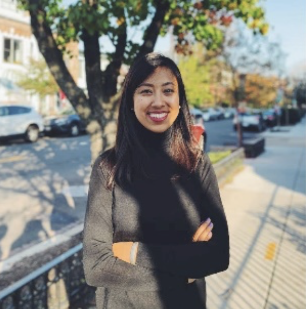 Smiling young Asian woman with medium length straight dark hair in a gray sweater standing outside