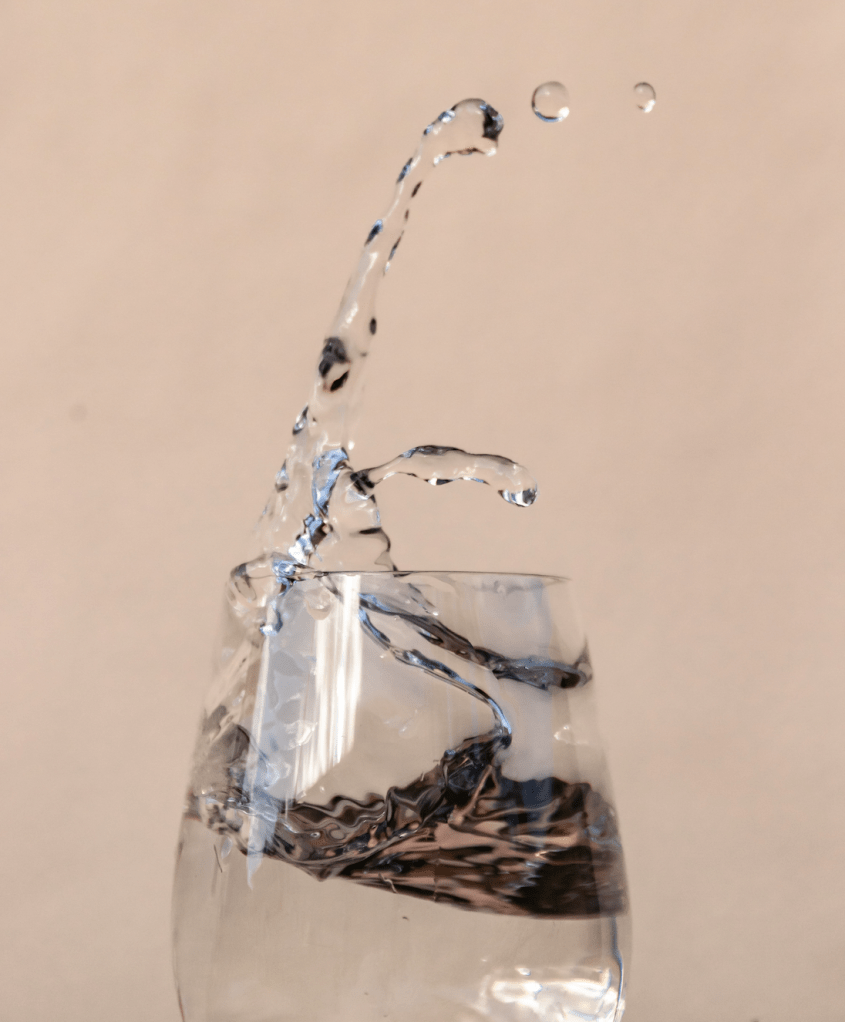 clear glass against a neutral background with water splashing dramatically into it